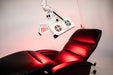 Red recliner chair with a medical device above it on a pink background