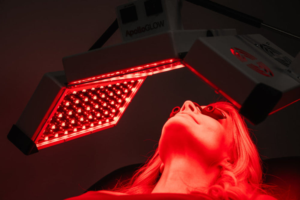 Person receiving red light therapy under a device labeled 'ApolloGLOW'.