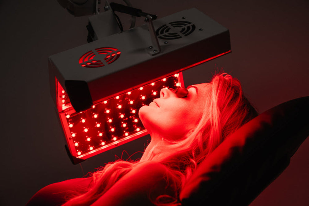 Person receiving red light therapy treatment with a device.