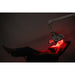 Person receiving red light therapy under a medical device with a dark background
