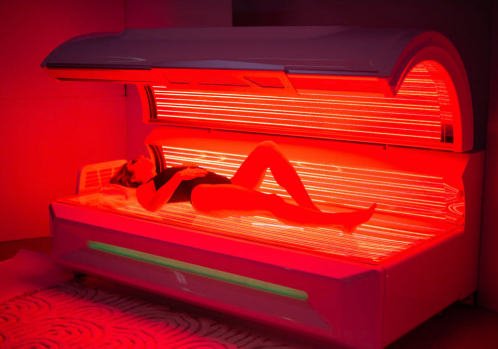 Woman lying inside a red light therapy bed, the bed is turned on