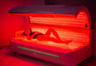 Woman lying inside a red light therapy bed, the bed is turned on