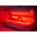 Woman lying inside a red light therapy bed, the bed is turned on