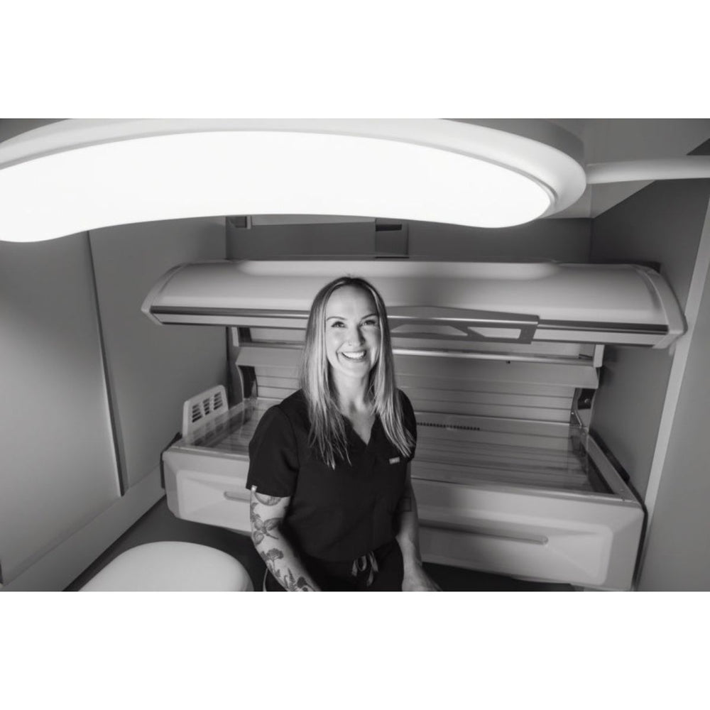 Spa worker standing in front of the Eros red light therapy bed