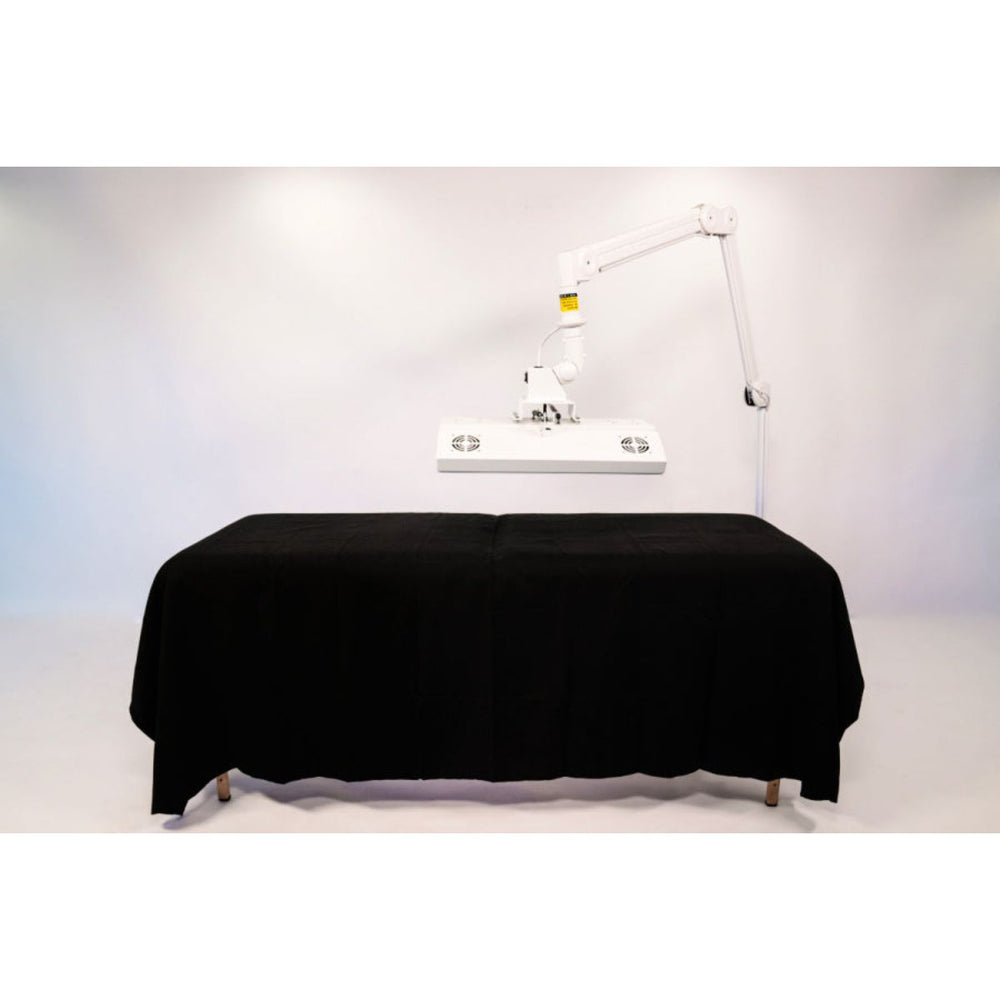 Massage table with black cover and overhead lighting on a white background