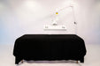Massage table with black cover and overhead lighting on a white background