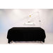 Massage table with black cover and overhead lighting on a white background