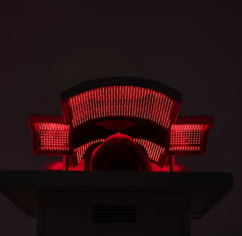 Person sitting in a red light therapy chair with a dark background