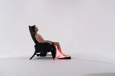 Person using a massage chair with red lights on a white background
