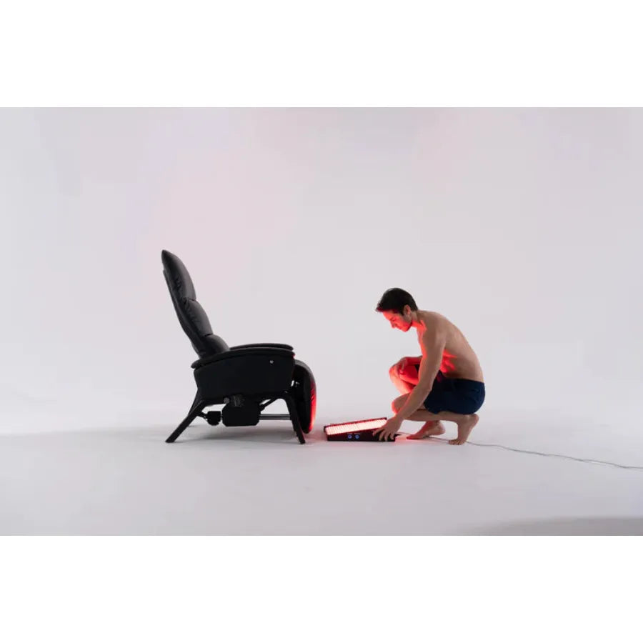 Person assembling a foot red light therapy device on a white background
