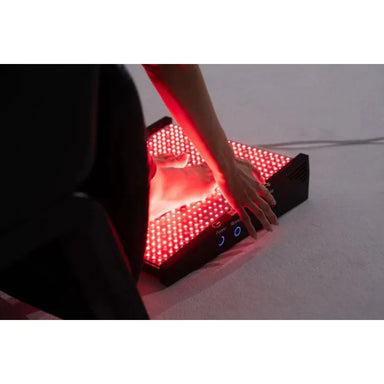 Person using a red light therapy device on a white surface