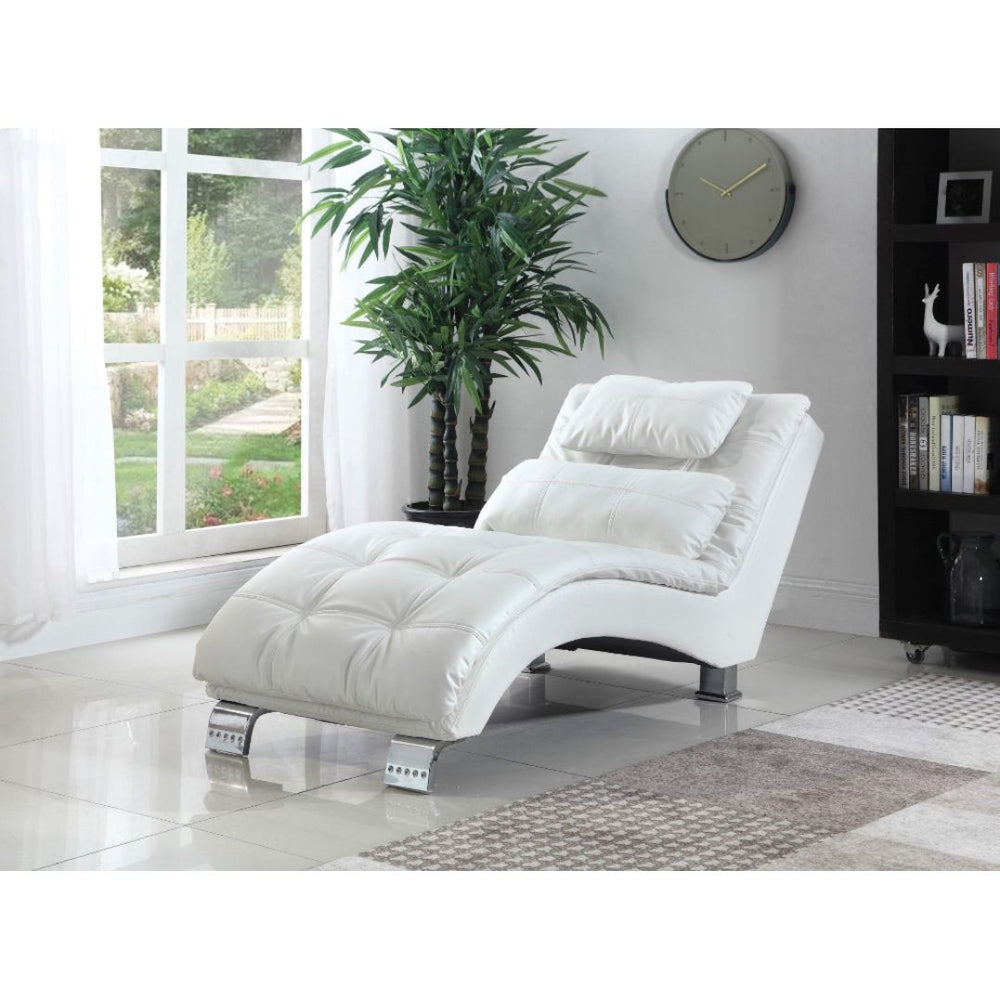 White chaise lounge chair in a room with a large window, plant, and bookshelf.
