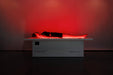 Person lying on a white platform with red lighting in a dark room