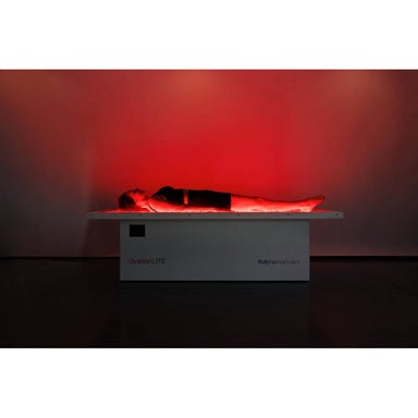 Person lying on a white platform with red lighting in a dark room