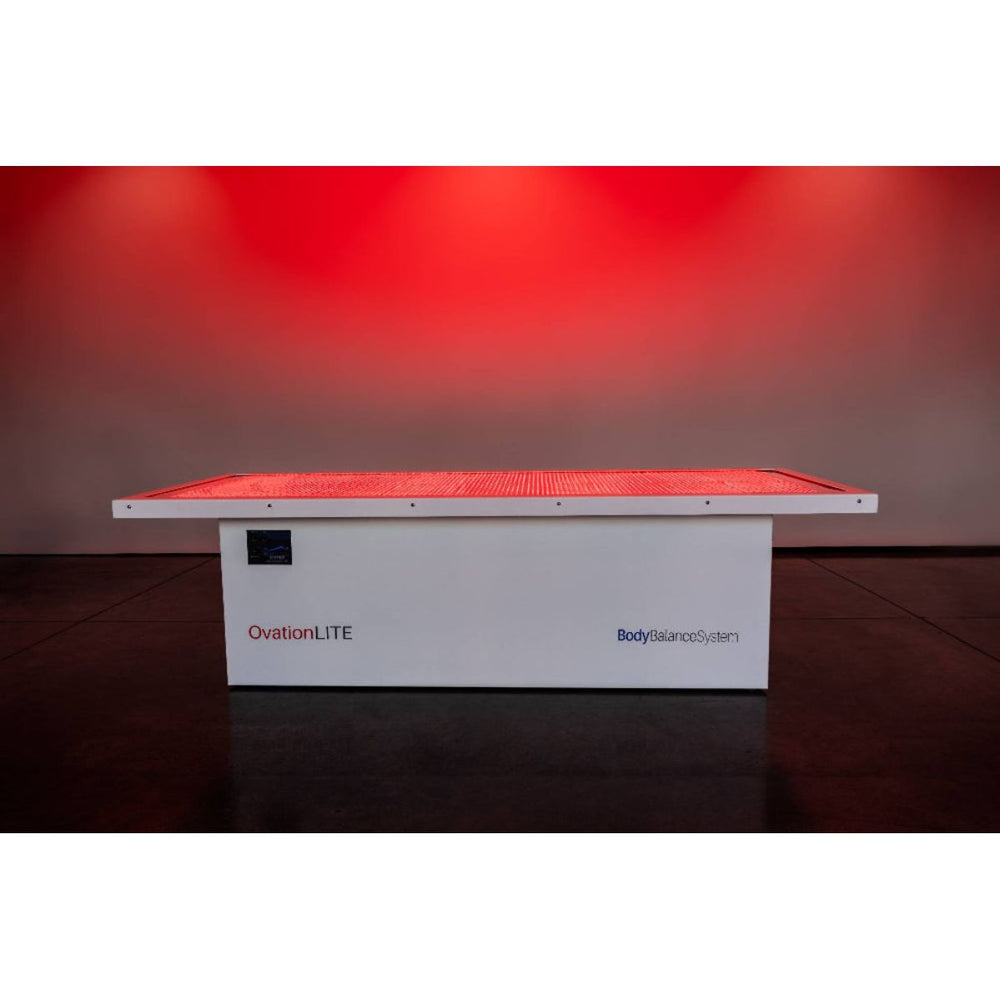 White device labeled 'OvationLITE' with red light on a dark floor against a red wall.