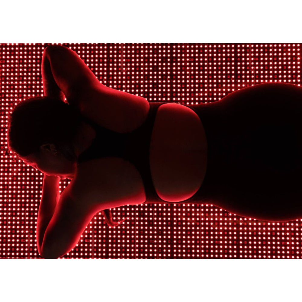 Person lying on a red LED floor with a close-up of their face.