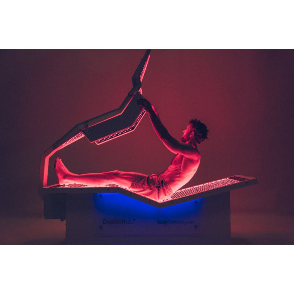 Person lying on a futuristic, open-air vehicle with red and blue lighting against a dark background