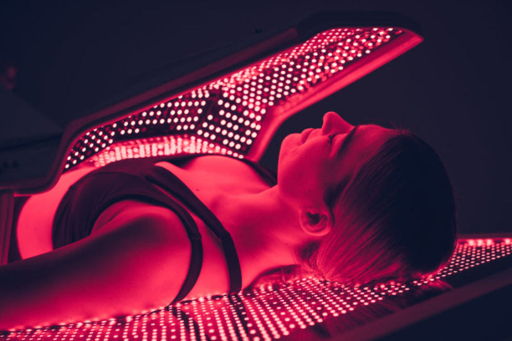 Person receiving red light therapy under a LED panel