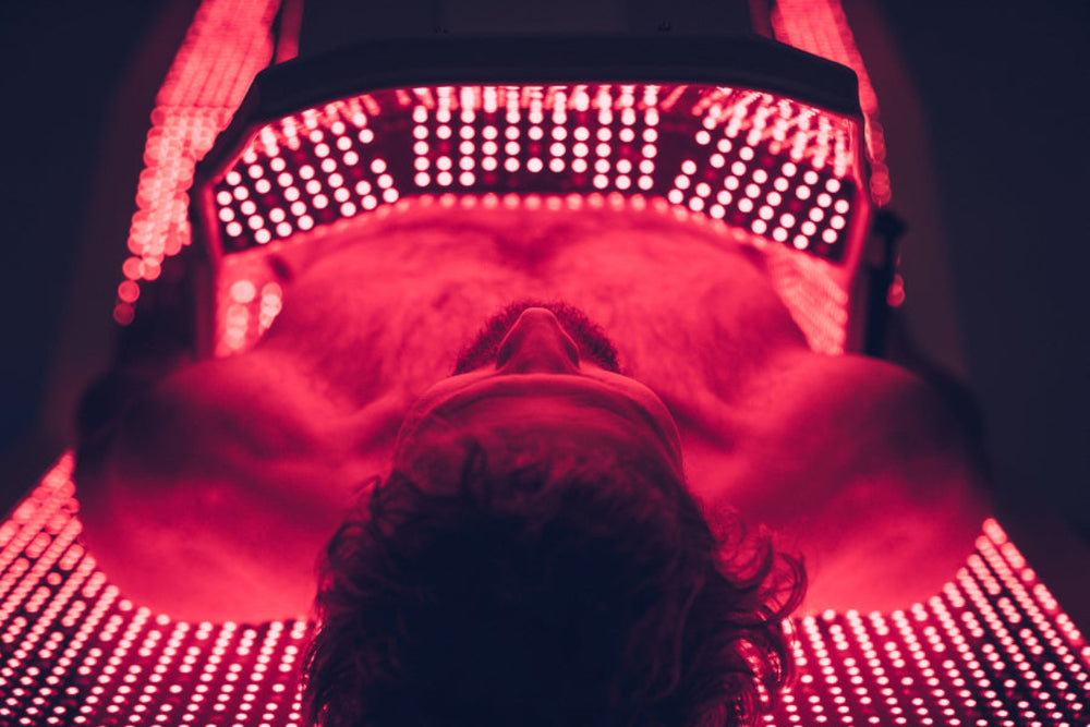 Person lying on a red light therapy mat with LED lights above them.