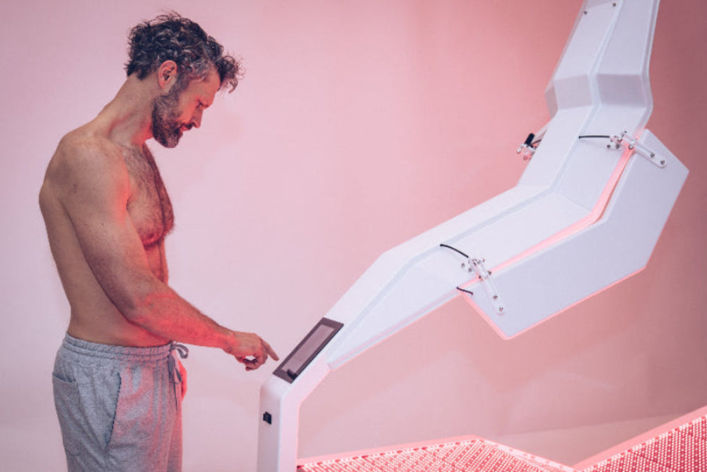 Man interacting with a futuristic medical device on a pink background
