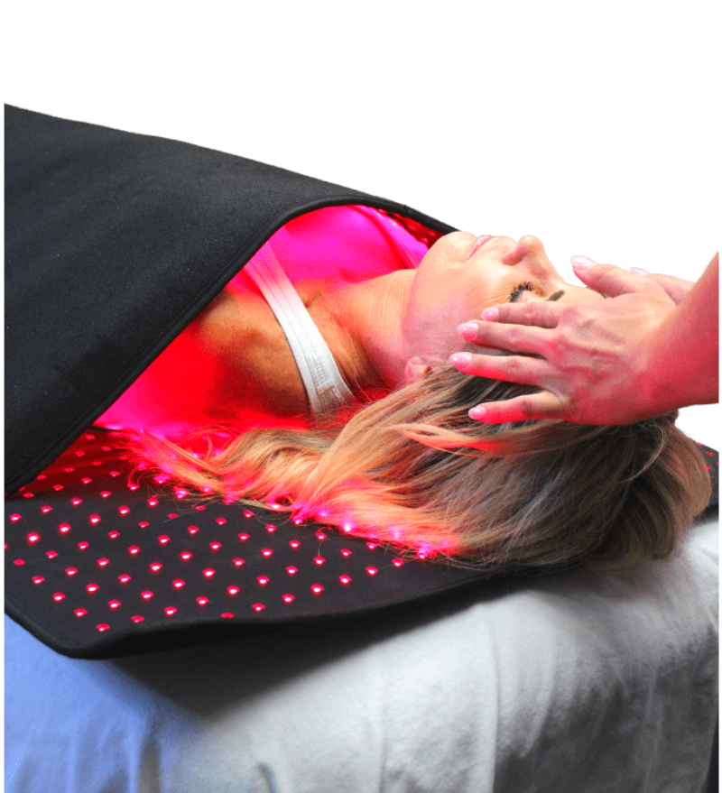 Person receiving red light therapy on a black mat with pink glowing lights.