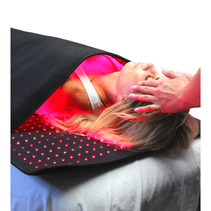 Person receiving red light therapy on a black mat with pink glowing lights.