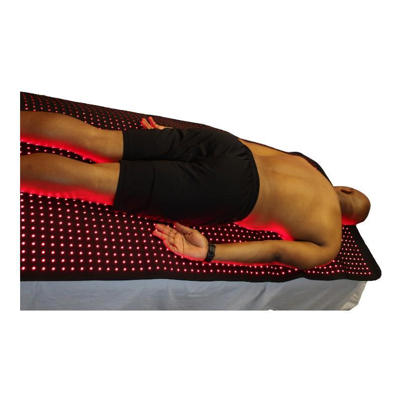 Person lying on a LED therapy mat with red lights on a white background