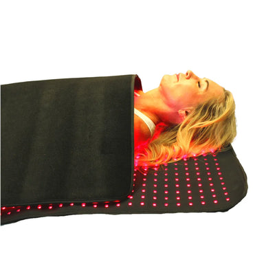 Person lying on a black mat with red LED lights on a white background