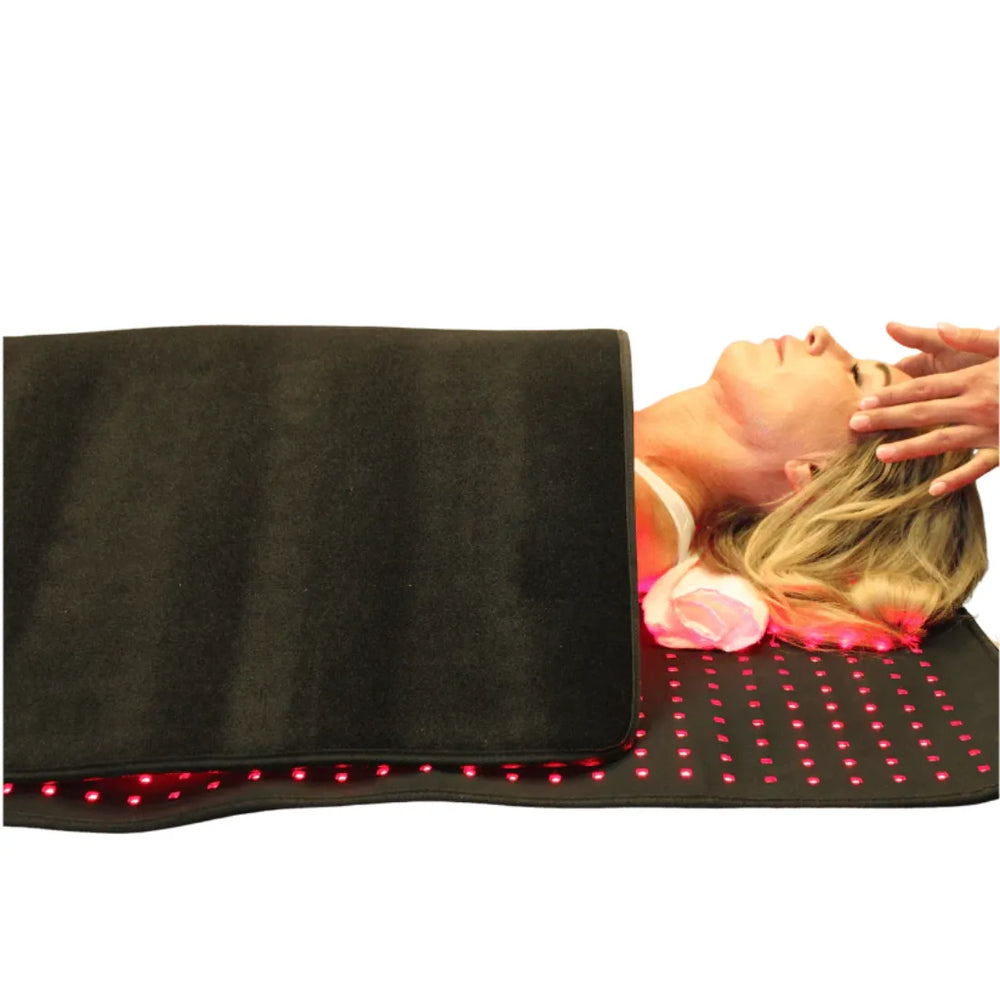 Person lying on a black mat with red LED lights, possibly for relaxation or therapy.
