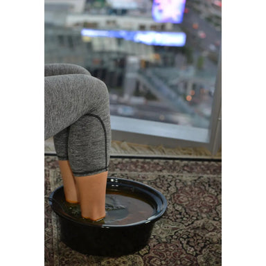Person sitting with feet in a bowl of water on a patterned rug with a cityscape in the background